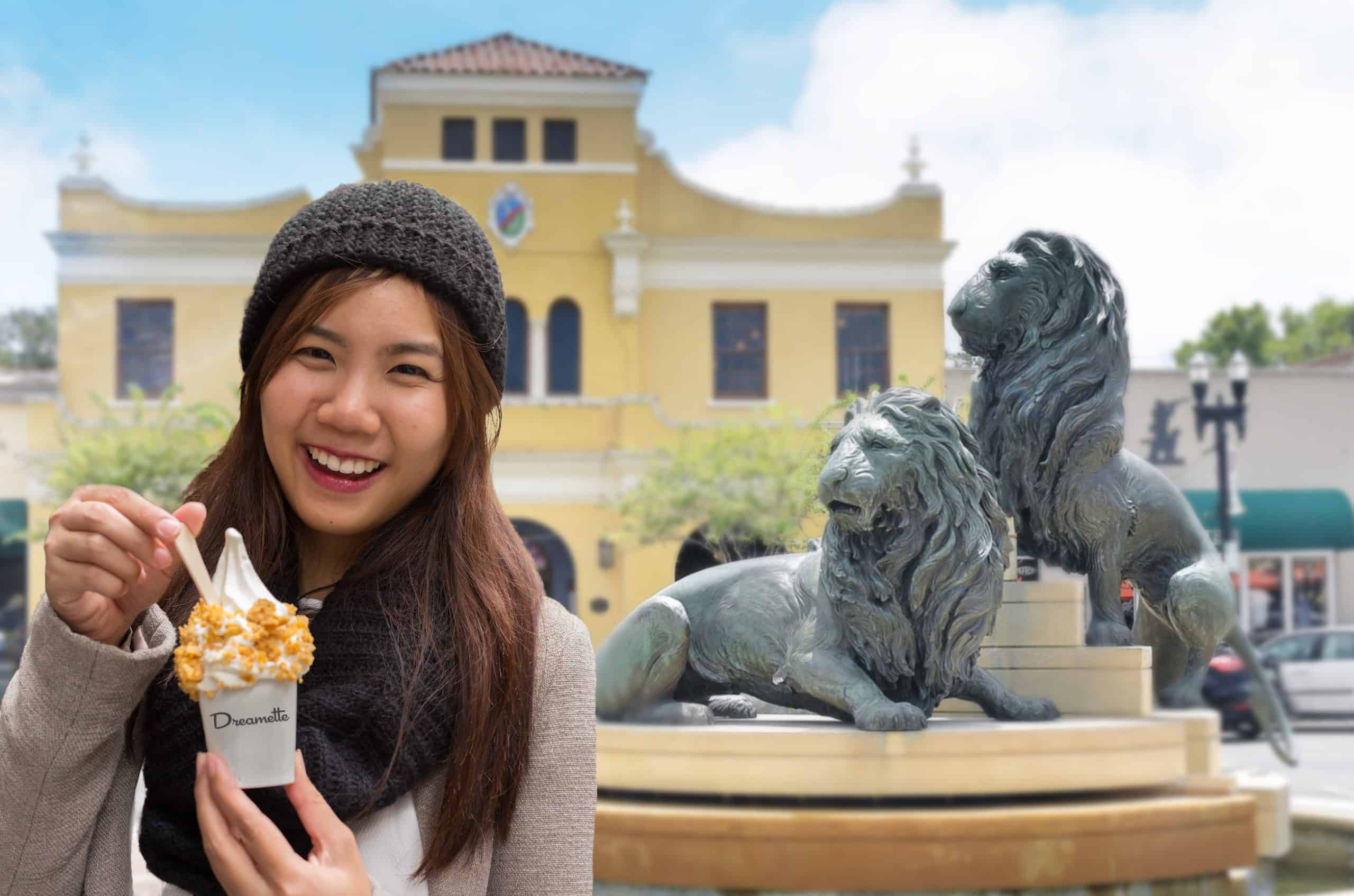Smiling girl eats a vegan vanilla ice cream sundae from San Marco Dreamette while standing in Balis Park in San Marco Square in Jacksonville Florida with two lion statues